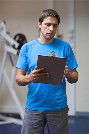 Serious personal trainer with clipboard standing in the gym Stock Photo - Premium Royalty-Free, Code: 6109-07498068