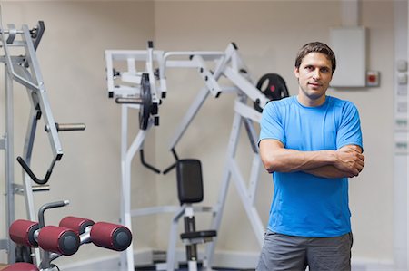 physical fitness - Portrait of a smiling trainer with arms crossed against lat machine in the gym Photographie de stock - Premium Libres de Droits, Code: 6109-07498070