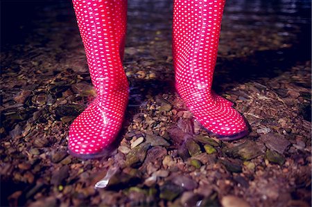 Close up low section of a woman in pink gumboots standing on pebbles Stock Photo - Premium Royalty-Free, Code: 6109-07498077