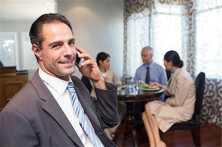 Businessman using cellphone with colleagues having meal Stock Photo - Premium Royalty-Free, Code: 6109-07600847