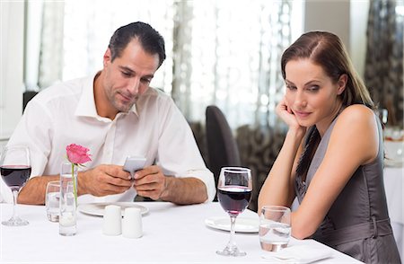 Couple with wine glass and cellphone dining in restaurant Foto de stock - Sin royalties Premium, Código: 6109-07600965