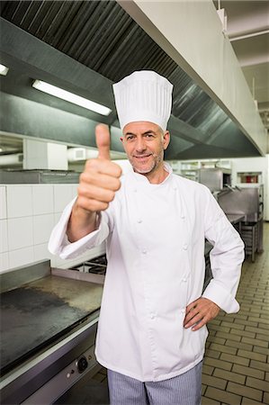 Happy chef looking at the camera giving thumbs up Stock Photo - Premium Royalty-Free, Code: 6109-07601041