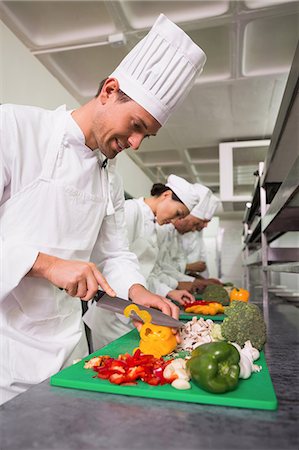 simsearch:6109-07601170,k - Row of trainee chefs slicing vegetables Stock Photo - Premium Royalty-Free, Code: 6109-07601088