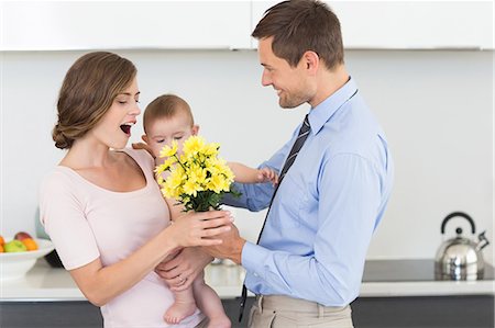 Father giving mother holding baby a bunch of yellow flowers Stock Photo - Premium Royalty-Free, Code: 6109-07601356