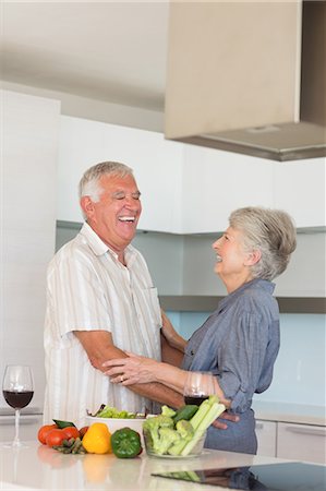 seniors happy - Happy senior couple hugging while preparing a meal Stock Photo - Premium Royalty-Free, Code: 6109-07601385