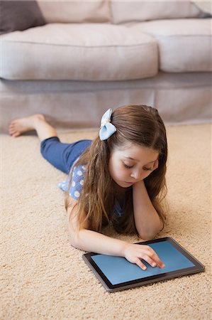Full length of a girl using digital tablet in living room Stock Photo - Premium Royalty-Free, Code: 6109-07601506