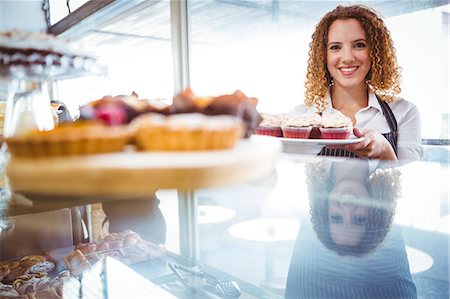 Pretty barista holding plate with cupcakes Foto de stock - Sin royalties Premium, Código: 6109-08203841