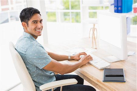 simsearch:6109-08203934,k - Portrait of smiling casual businessman working with computer and looking at camera Stock Photo - Premium Royalty-Free, Code: 6109-08203894