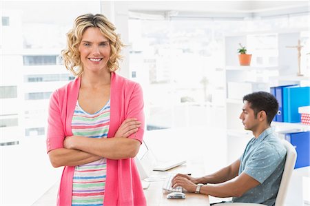 simsearch:6109-08203934,k - Portrait of smiling woman working in front of her colleague Stock Photo - Premium Royalty-Free, Code: 6109-08203912