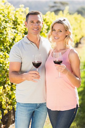 simsearch:6109-08204218,k - Portrait of smiling couple holding wineglass and standing next to grapevine Stock Photo - Premium Royalty-Free, Code: 6109-08204007