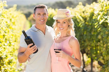 simsearch:6109-08204218,k - Portrait of smiling couple holding wine and standing next to grapevine Stock Photo - Premium Royalty-Free, Code: 6109-08204004