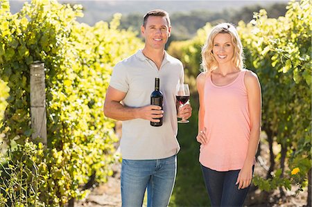 simsearch:6109-08204218,k - Smiling couple holding wine and standing next to grapevine Stock Photo - Premium Royalty-Free, Code: 6109-08204005