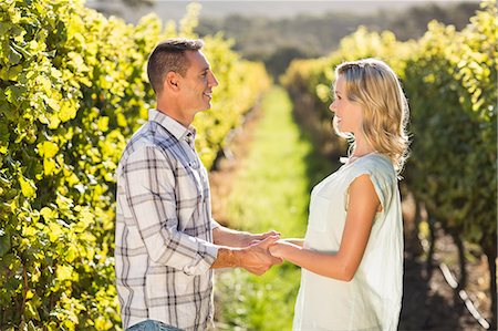 simsearch:6109-08204218,k - Smiling couple holding hands and standing next to grapevine Stock Photo - Premium Royalty-Free, Code: 6109-08204018