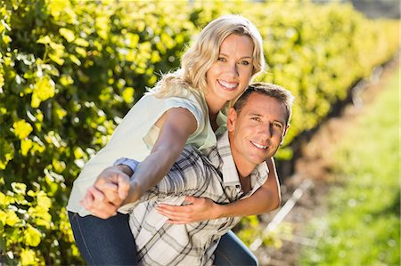 simsearch:6109-08204218,k - Portrait of smiling man giving his woman a piggyback next to grapevine Stock Photo - Premium Royalty-Free, Code: 6109-08204023