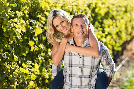 simsearch:6109-08204218,k - Portrait of smiling man giving his woman a piggyback next to grapevine Stock Photo - Premium Royalty-Free, Code: 6109-08204022