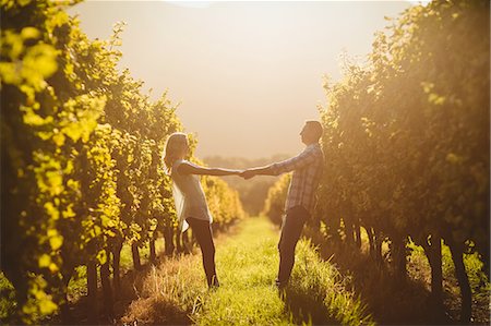 simsearch:6109-08204218,k - Couple holding hands and leaning back between grapevine Stock Photo - Premium Royalty-Free, Code: 6109-08204031