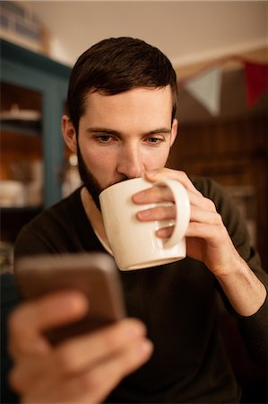 Handsome hipster checking his phone Stock Photo - Premium Royalty-Free, Code: 6109-08390050