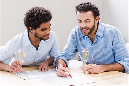 simsearch:6109-08390293,k - Happy gay couple drinking champagne and writing on newspaper Stock Photo - Premium Royalty-Free, Code: 6109-08390290