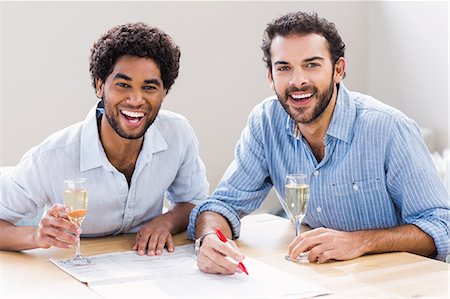 simsearch:6109-08390293,k - Happy gay couple drinking champagne and writing on newspaper Stock Photo - Premium Royalty-Free, Code: 6109-08390291