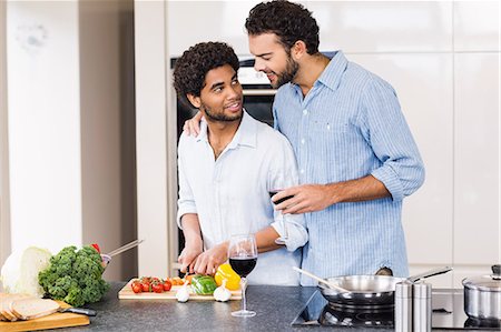 simsearch:6109-08390293,k - Happy gay couple drinking wine and slicing vegetables Stock Photo - Premium Royalty-Free, Code: 6109-08390292