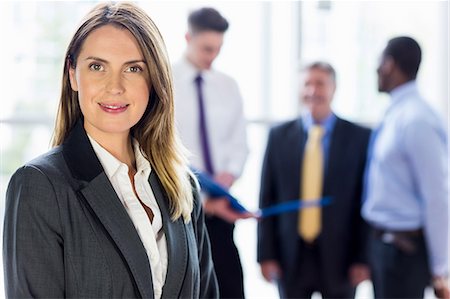 simsearch:6109-06684997,k - Businesswoman posing while her colleagues in background Stock Photo - Premium Royalty-Free, Code: 6109-08394984