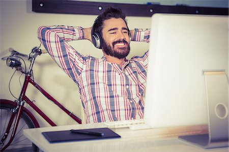 Happy businessman listening music while relaxing with arms raised Stock Photo - Premium Royalty-Free, Code: 6109-08395830
