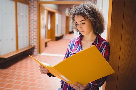 Pretty student reading file in hallway Stock Photo - Premium Royalty-Free, Code: 6109-08396326