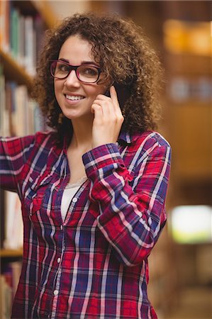 simsearch:614-06973867,k - Pretty student in the library on phone Photographie de stock - Premium Libres de Droits, Code: 6109-08396569