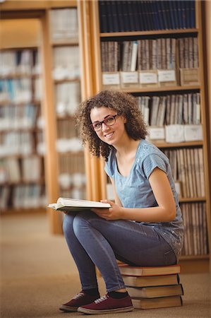 student campus - Pretty student in library sitting on books Stock Photo - Premium Royalty-Free, Code: 6109-08396625