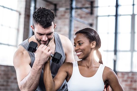 simsearch:6109-08398593,k - Personal trainer working with client holding dumbbell Stock Photo - Premium Royalty-Free, Code: 6109-08396907
