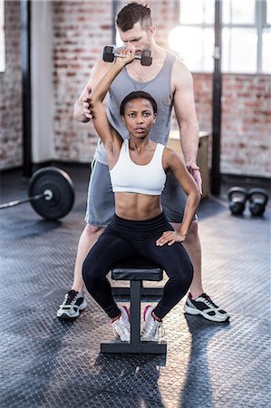 simsearch:6109-08398593,k - Personal trainer working with client holding dumbbell Stock Photo - Premium Royalty-Free, Code: 6109-08396905