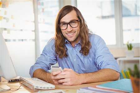 person on office desk phone - Portrait of creative businessman smiling while holding smartphone Stock Photo - Premium Royalty-Free, Code: 6109-08397399