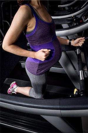 simsearch:6109-08398593,k - Pregnant woman touching belly on treadmill Stock Photo - Premium Royalty-Free, Code: 6109-08398598