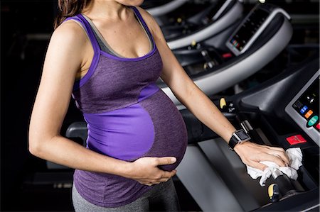simsearch:6109-08398593,k - Pregnant woman touching belly on treadmill Stock Photo - Premium Royalty-Free, Code: 6109-08398620