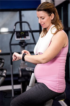 simsearch:6109-08398593,k - Pregnant woman riding bike looking at her smart watch Stock Photo - Premium Royalty-Free, Code: 6109-08398709