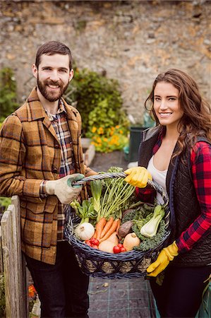 smiling couple in vegetable garden - Proud couple showing basket of vegetables Stock Photo - Premium Royalty-Free, Code: 6109-08398985