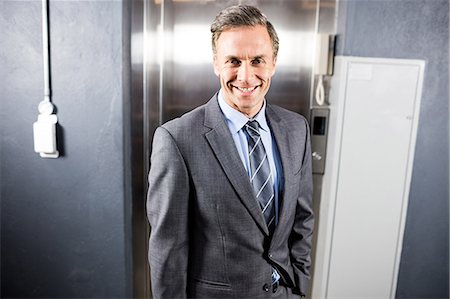 simsearch:6109-06684997,k - Smiling businessman standing front of elevator Stock Photo - Premium Royalty-Free, Code: 6109-08399247