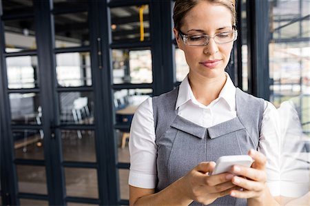 Portrait of a serious businesswoman typing on her phone Stock Photo - Premium Royalty-Free, Code: 6109-08399218