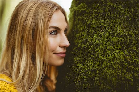 simsearch:6109-08481688,k - Beautiful blonde woman standing next to a tree trunk in the woods Photographie de stock - Premium Libres de Droits, Code: 6109-08481696