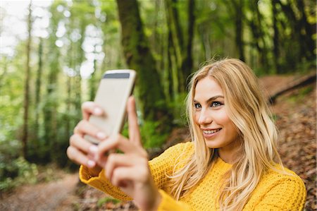 simsearch:6109-08481688,k - Beautiful blonde woman taking picture in the woods Photographie de stock - Premium Libres de Droits, Code: 6109-08481699