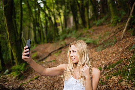 simsearch:6109-08481688,k - Beautiful blonde woman taking selfie in the woods Photographie de stock - Premium Libres de Droits, Code: 6109-08481727