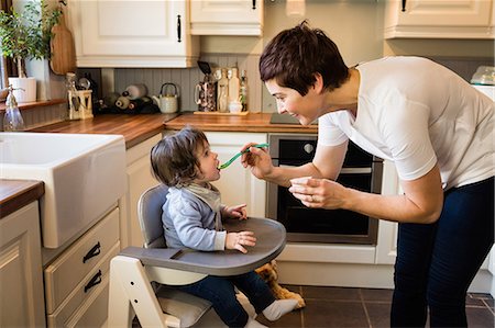simsearch:6109-08390041,k - Cute mother feeding her baby in the kitchen Stock Photo - Premium Royalty-Free, Code: 6109-08481802
