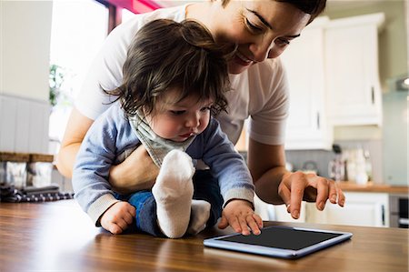 simsearch:6109-08390041,k - Cute mother showing tablet to her baby in the kitchen Stock Photo - Premium Royalty-Free, Code: 6109-08481810