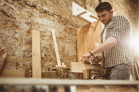 Carpenter working on his craft in a dusty workshop Stock Photo - Premium Royalty-Free, Code: 6109-08481943