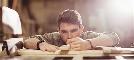 studio light photography - Happy carpenter working on his craft in a dusty workshop Stock Photo - Premium Royalty-Free, Code: 6109-08481921