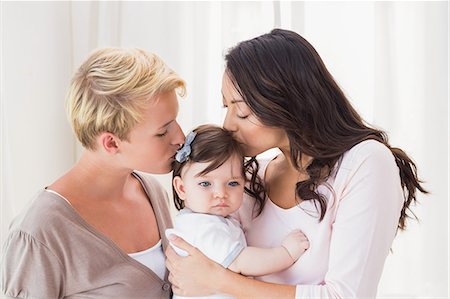 Standing lesbian couple kissing their baby girl Photographie de stock - Premium Libres de Droits, Code: 6109-08488597