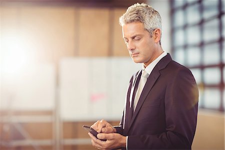 simsearch:6109-06685044,k - Businessman using his smart phone at the office Stock Photo - Premium Royalty-Free, Code: 6109-08488706