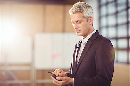 elegant - Businessman using his smart phone at the office Stock Photo - Premium Royalty-Free, Code: 6109-08488706