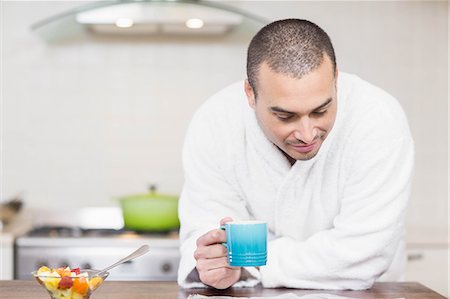 simsearch:6108-05856772,k - Focused man drinking coffee while reading a magazine in the kitchen at home Stock Photo - Premium Royalty-Free, Code: 6109-08489028