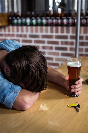 Drunk man sleeping at the bar holding his pint Stock Photo - Premium Royalty-Free, Code: 6109-08489509